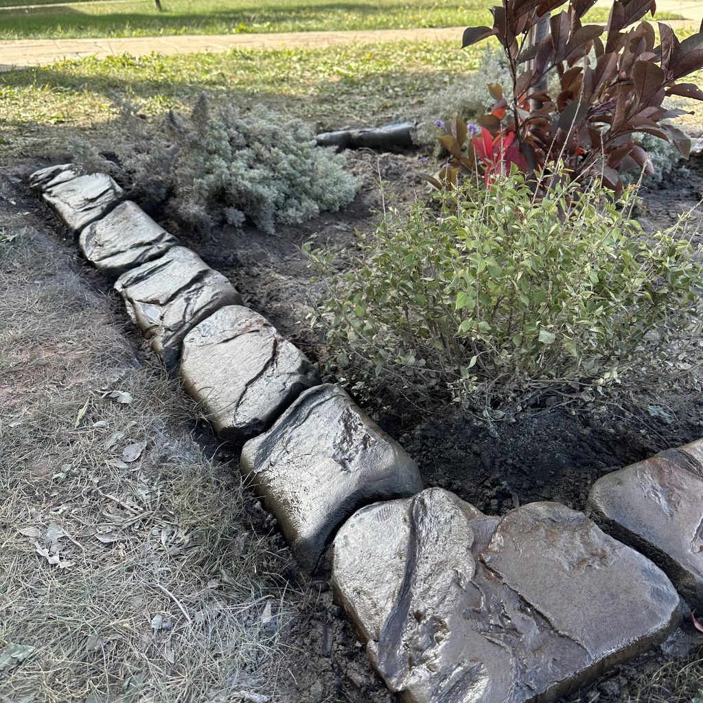 Image of hand carved concrete curbing around a customer's garden bed.