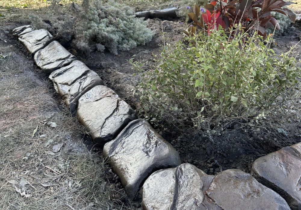 Image of hand carved concrete curbing around a customer's garden bed.